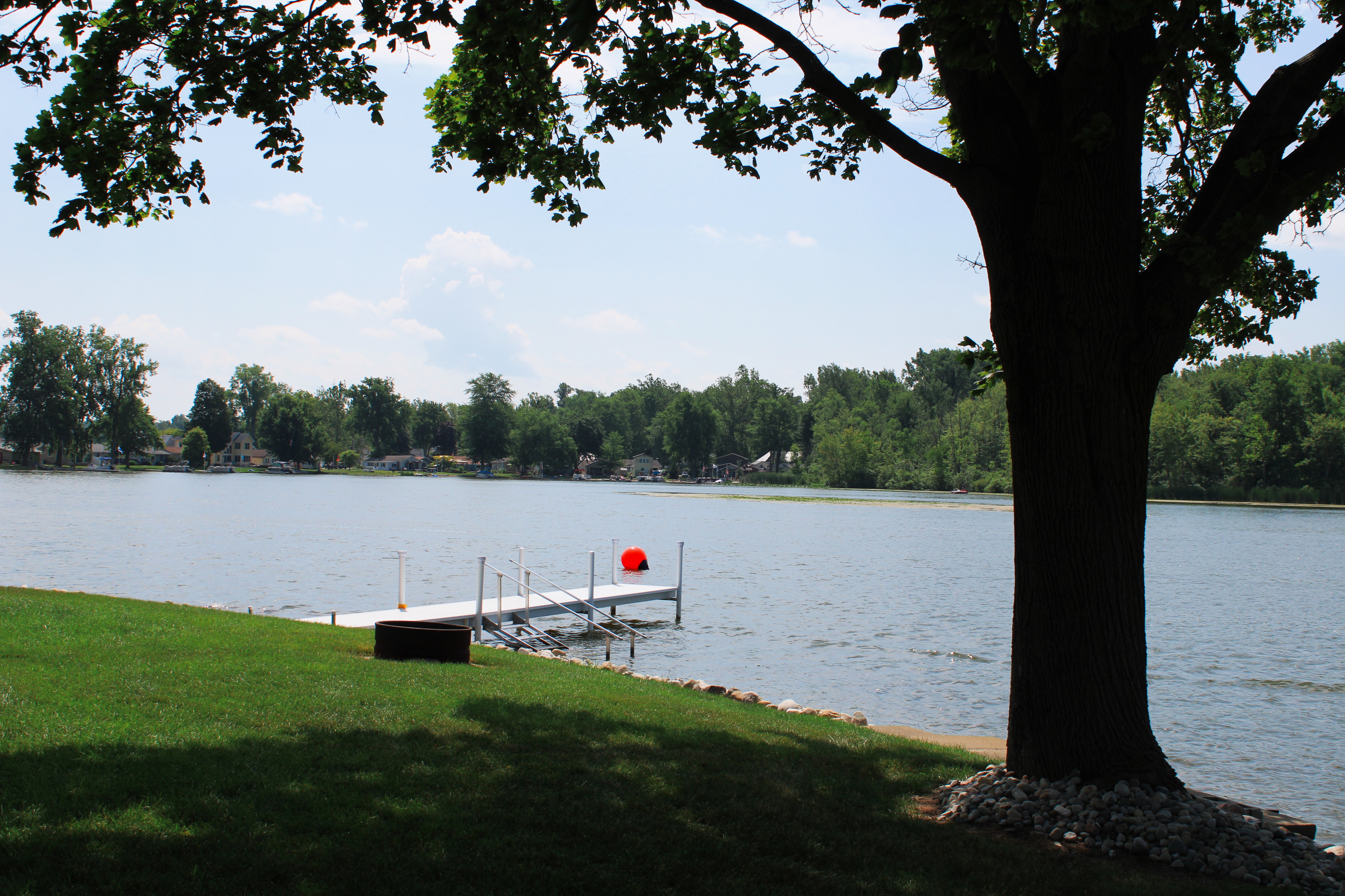 A large tree is featured in the foreground, overlooking a private pier at a lake in Indiana vacation rental.