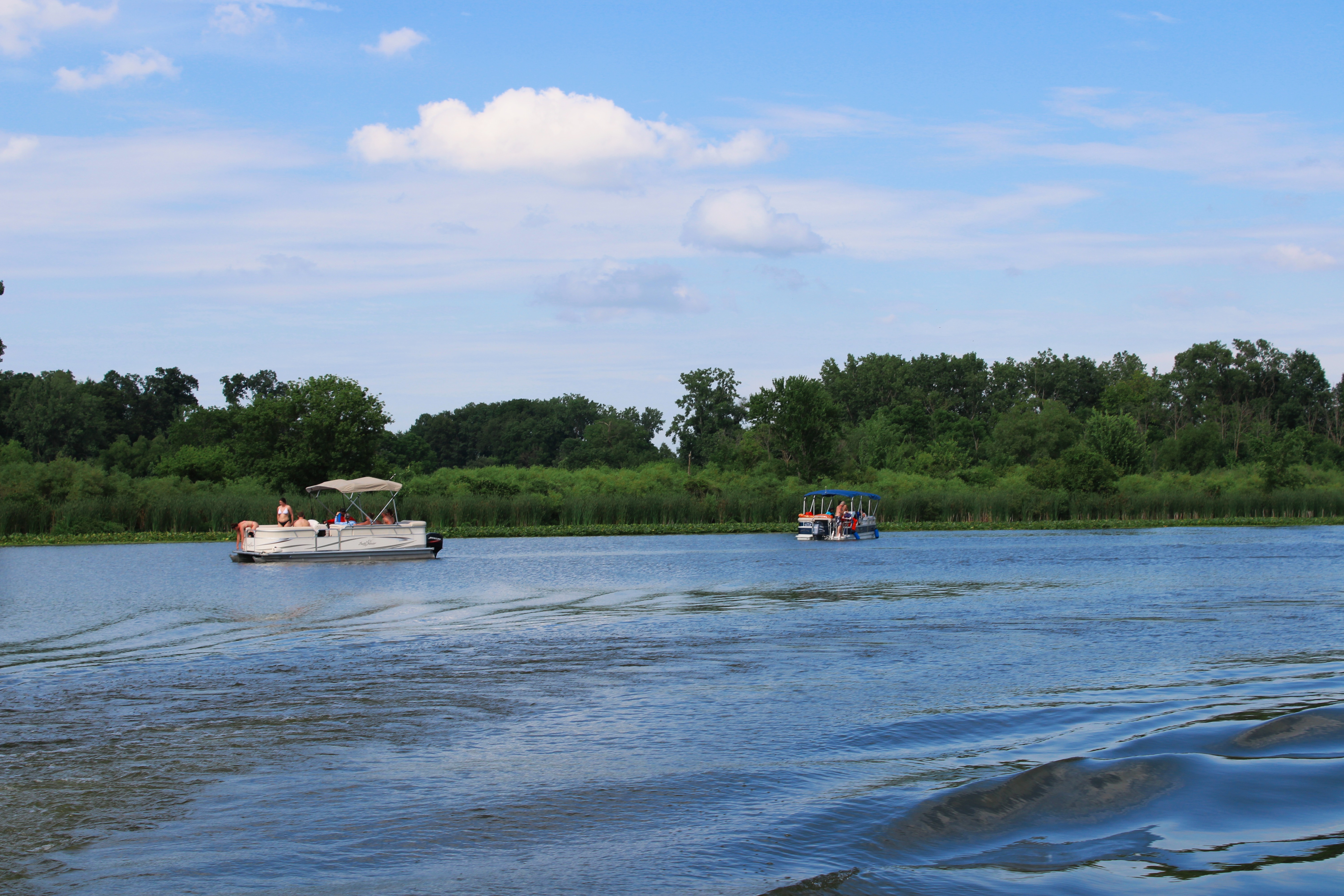 Boats glide across smooth lake surrounded by lush greenery on vacation getaway