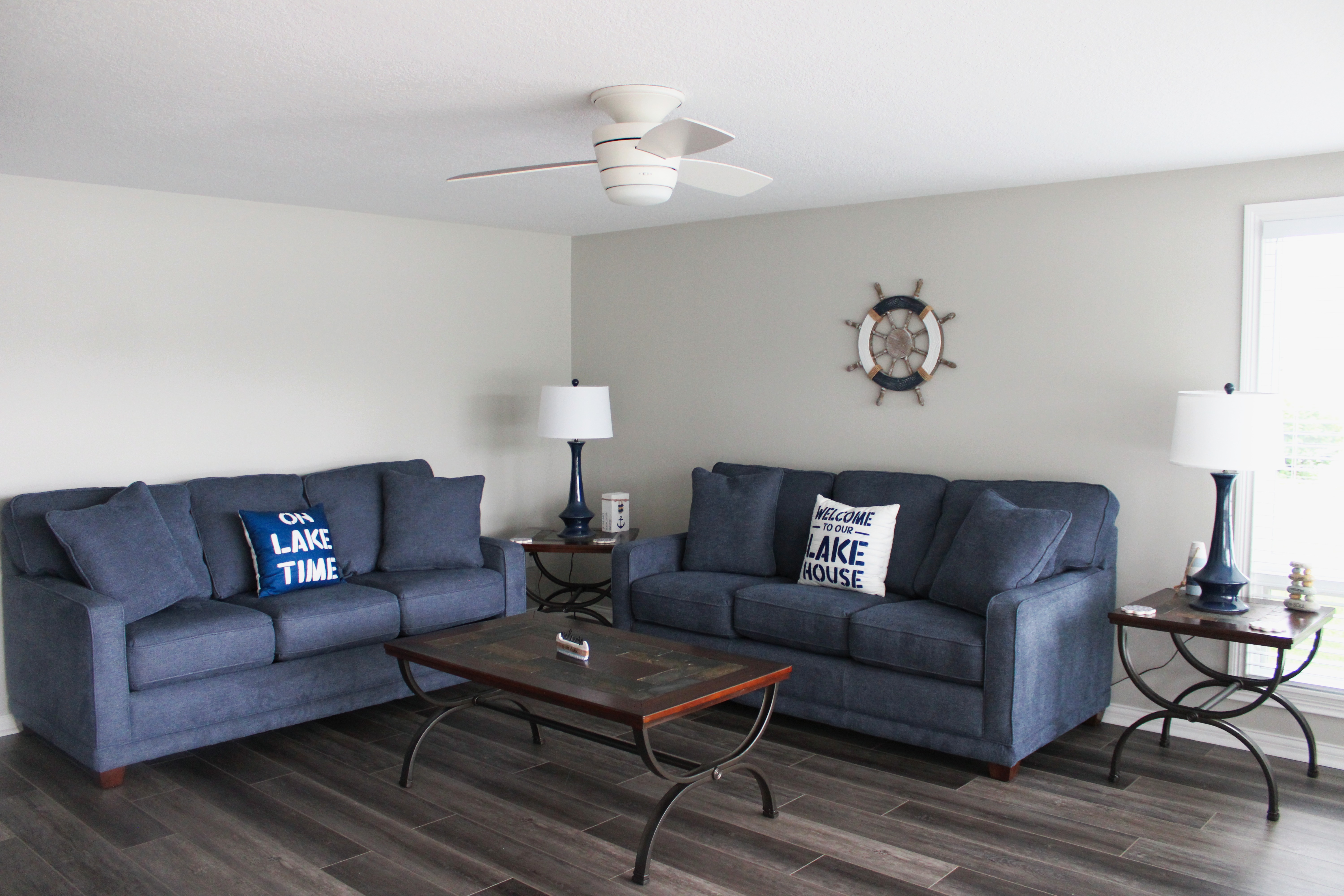 A blue couch in a cozy family room of a lakefront rental, with natural light streaming through the windows.