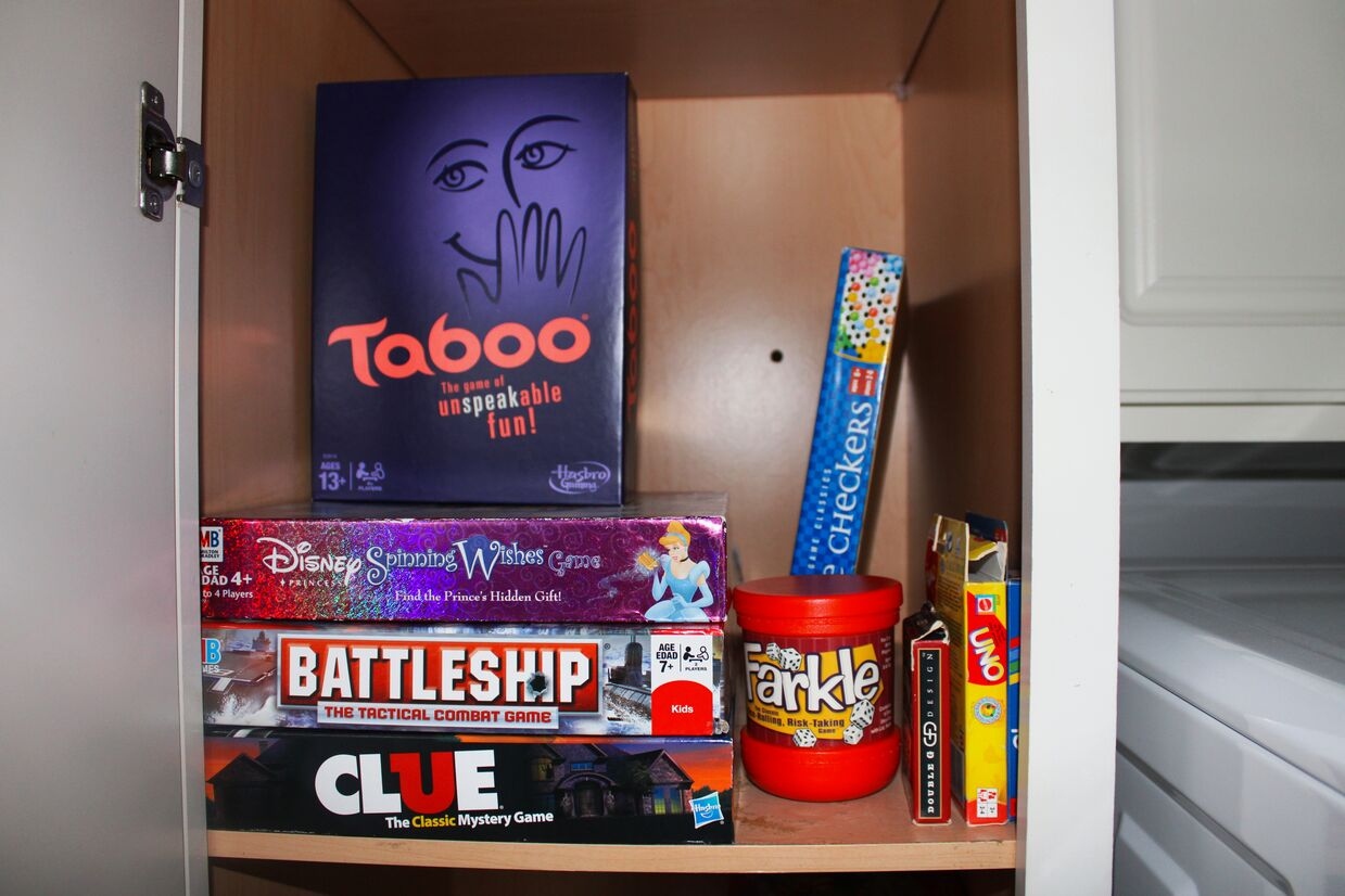 A cabinet in the laundry room is stocked with classic board games and puzzles, offering a fun way to unwind indoors.